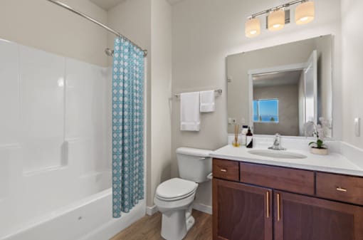 A bathroom with a white toilet, a sink, and a shower with a blue curtain.