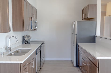 A kitchen with a sink, refrigerator, and microwave.