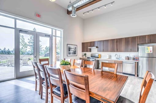 A dining room with a wooden table and chairs, a fridge, and a window with a view of the outdoors.