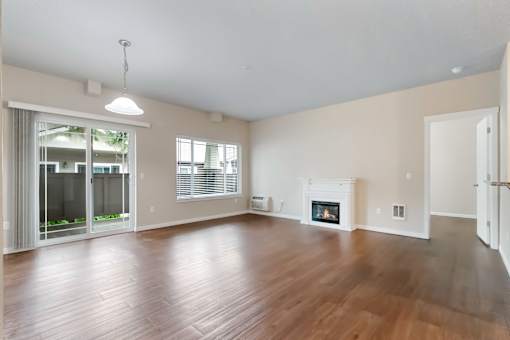 A large, empty room with a fireplace and a sliding glass door leading to a balcony.