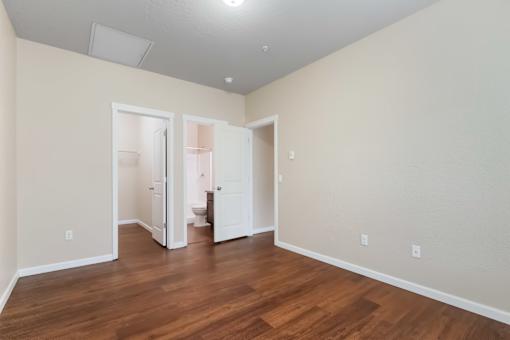 A room with a wooden floor and two open doors.