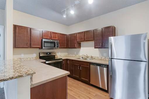 A kitchen with brown cabinets and a granite counter.