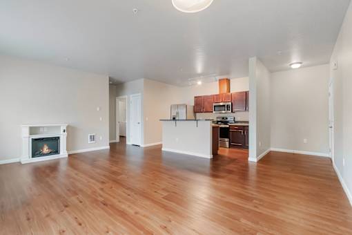A large open living room with a fireplace and a kitchen area in the background.