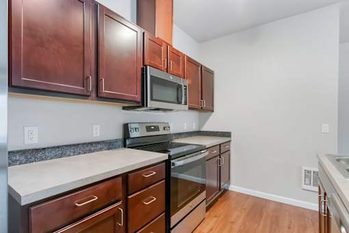 A kitchen with brown cabinets and a microwave above the stove.