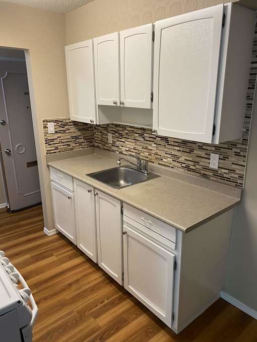 a kitchen with white cabinets and a wooden floor