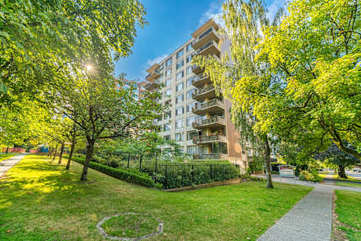 A sunny day in a park with a building in the background.