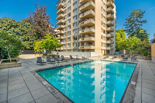 A large swimming pool in front of a tall apartment building.