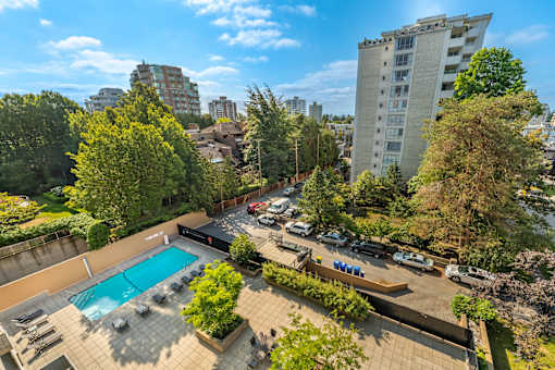 A swimming pool surrounded by trees and a parking lot.