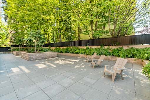 A patio with chairs and a table surrounded by a fence and trees.