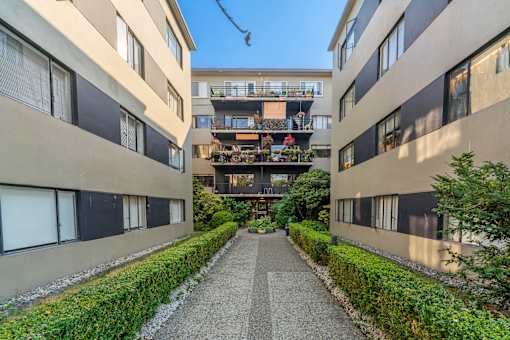 A long, narrow walkway separates two buildings with balconies.