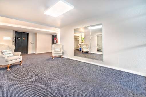 A spacious room with a blue carpet and a mirror on the wall.