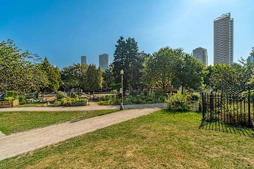 A park with a dirt path and a tall city skyline in the background.