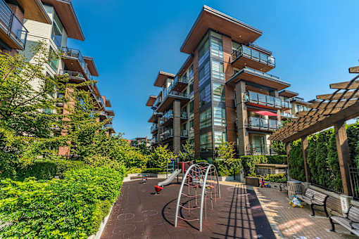 A playground with a slide and a climbing frame is situated in a courtyard surrounded by residential buildings.