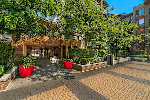 A courtyard with a building in the background and red planters in the foreground.