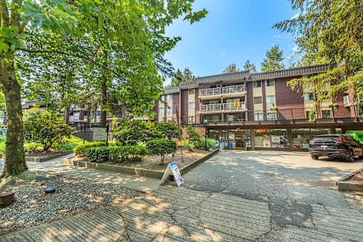 A parking lot in front of a multi-story apartment building.