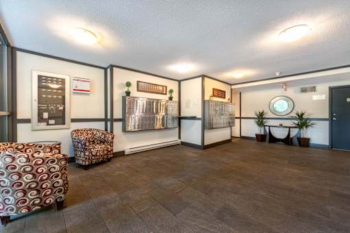 A room with a brown floor and a white wall with a clock on it.