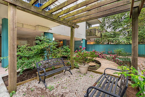 A wooden pergola over a bench in a garden.