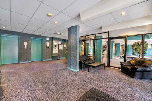 A room with a carpeted floor and a column in the middle.