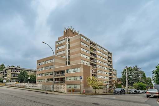 A large apartment building with a parking lot in front.