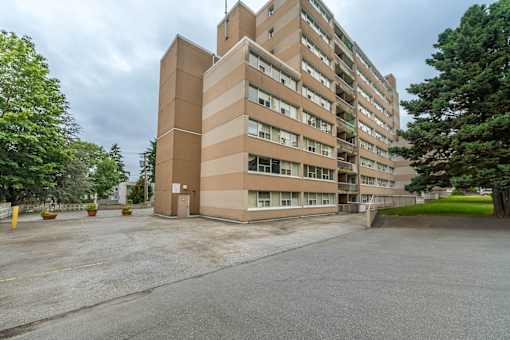 A large beige building with a parking lot in front.