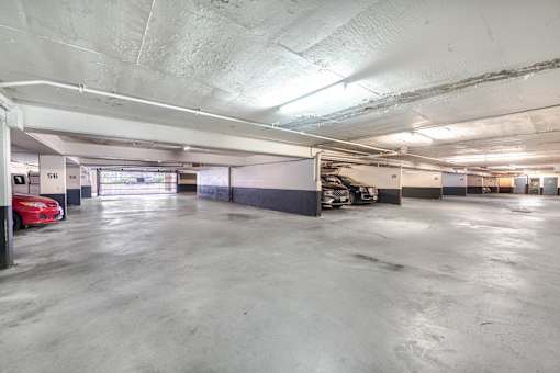 A parking garage with a red car parked in the first bay.