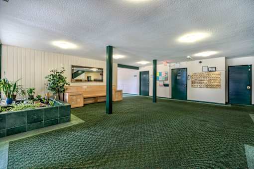 A room with a bench, a planter, and a bulletin board on the wall.
