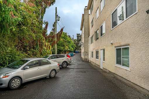 A street with parked cars and apartment buildings on both sides.