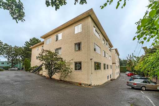 A beige building with a parking lot in front.