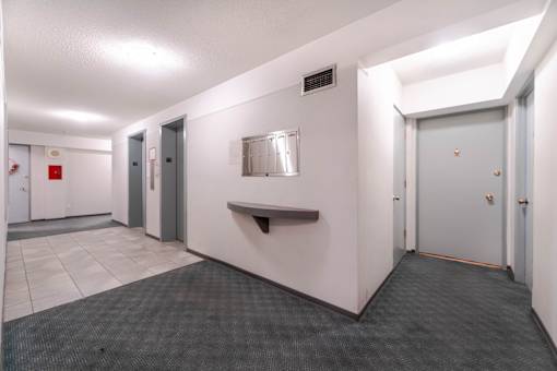 A hallway with a bench, doors, and a fire extinguisher.