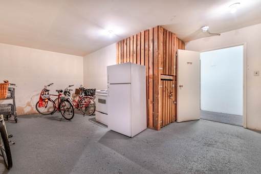 A room with a white fridge and a wooden wall.