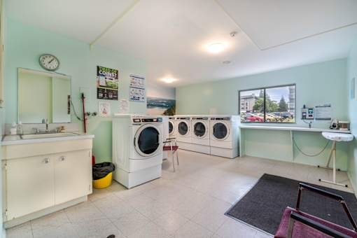 A laundry room with a washing machine, dryer, and ironing board.