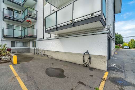 A parking lot in front of a white building with balconies.