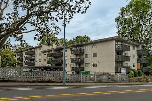 Apartment building with a fence and trees in front.