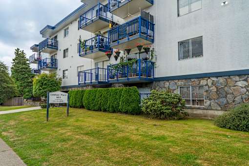 A white building with blue railings and a sign that says Lindsey Place.