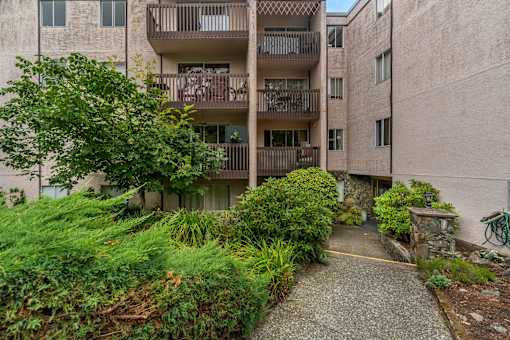 A concrete pathway leads to a building with a balcony.