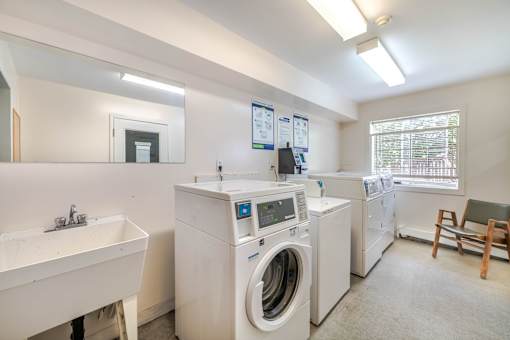 A laundry room with a washer and dryer, a sink, and a chair.