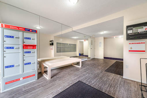 A room with a bench, a mirror, and a TV mounted on the wall.