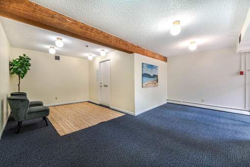 A room with a blue carpet and a wooden beam on the ceiling.