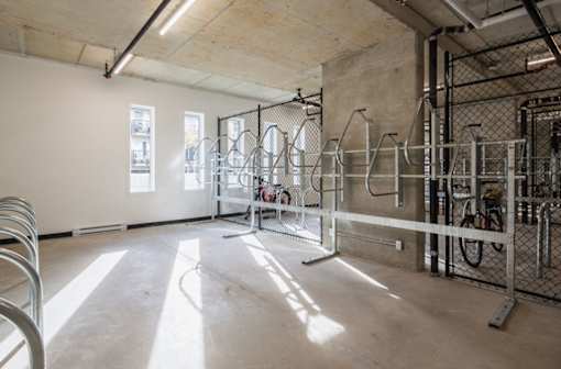 A large, empty room with a bicycle rack and windows.