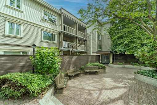 A courtyard surrounded by apartment buildings with a bench and a tree.