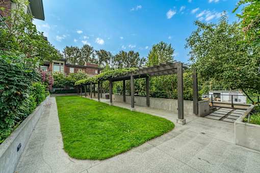 A sunny day at a park with a wooden pergola.