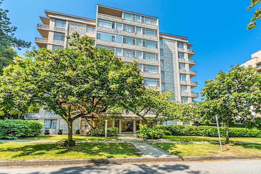 A large apartment building with a tree in front.
