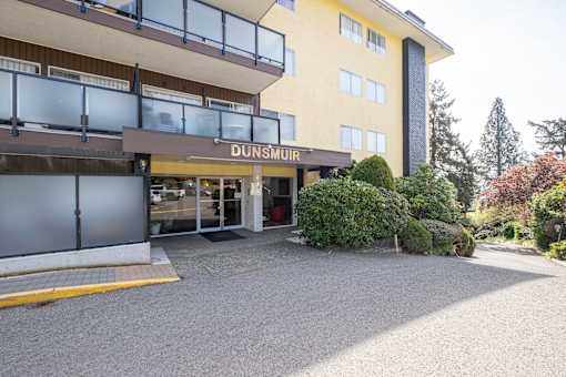 A yellow building with a glass entrance and a sign that says DUNSMUIR.