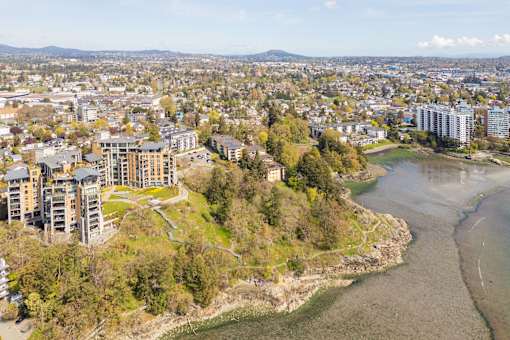 A river flows through a city with apartment buildings on the left and a large body of water on the right.