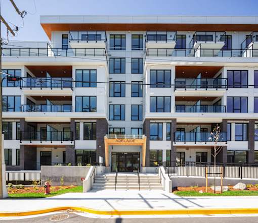 The front of a multi-story apartment building with a fire hydrant in the foreground.