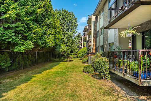 A balcony with a table and chairs overlooks a grassy area.