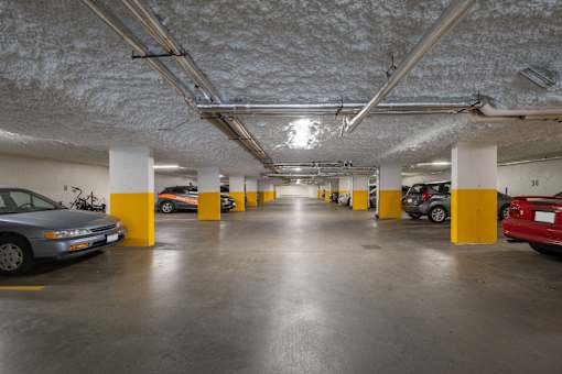 A parking garage with cars parked and yellow poles.