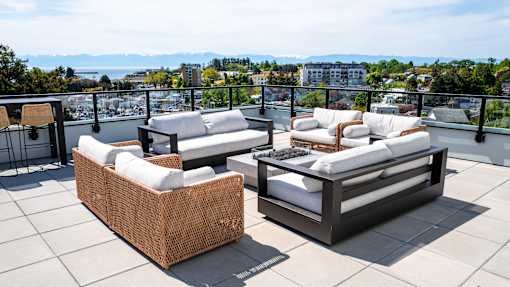 Two white couches on a patio with a view of the water and mountains.