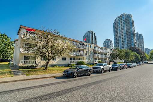 A row of cars parked on the side of a road in front of a building.