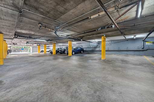 A parking garage with concrete floors and yellow poles.